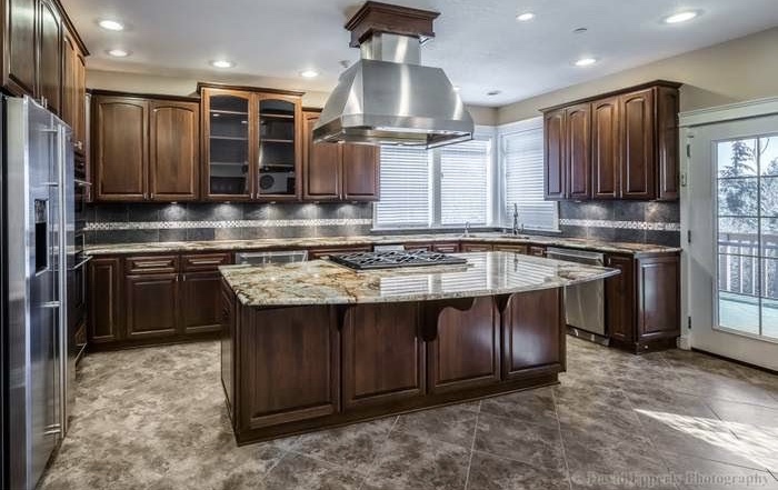 Finished kitchen with dark cabinetry and granite island